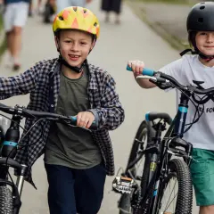 Dwóch chłopców w kaskach z rowerami. Idealny rower dla 9 latka to taki, który sprawia radość i zachęca do aktywności.