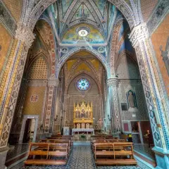 Interno di un santuario in Emilia Romagna, con affreschi colorati, volte decorate e un altare dorato.