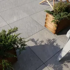 Nowe, szare płyty tarasowe ułożone na betonie, z drewnianymi donicami i zielenią.