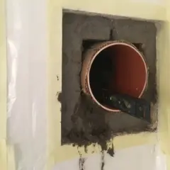 Inmurningsstos montering. Ett rör sitter i en betongvägg, en vattenpass kontrollerar att det är rakt.