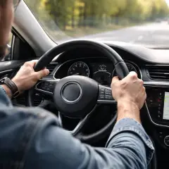 Mężczyzna prowadzi samochód, czuć drgania kierownicy przy 120 km/h. Na ekranie nawigacja.