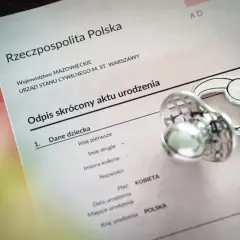 Odpis aktu urodzenia z Polski, obok smoczek. Dokument zawiera dane dziecka, w tym miejsce na wpisanie imion, które mogą być jednymi z najpopularniejszych imion.