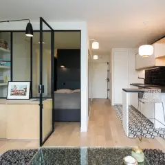 Interno di moderni mini appartamenti con zona giorno, cucina a vista e camera da letto separata da vetrata.