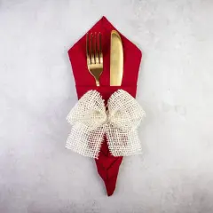 Elegancko złożona czerwona serwetka z widelcem i nożem, ozdobiona jutowym kokardą. Prosty sposób, jak położyć serwetki na stole, by zachwycić gości.