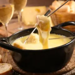 Une délicieuse fondue au beaufort, avec du pain croustillant et un verre de vin blanc.
