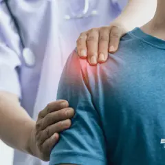 Lekarz wspiera pacjenta z bólem barku, wskazując na problem z płynem w kaletce podbarkowej. Leczenie bólu barku.