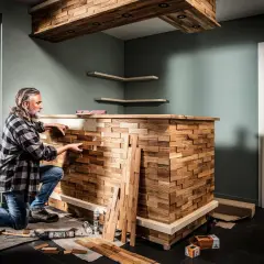 Mann baut mit Holzstücken eine einzigartige Bar. Heimwerken: bar selber bauen mit Stil.