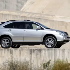 Srebrny Lexus RX 400h na tle betonowej ściany. Choć piękny, warto znać jego wady przed zakupem.