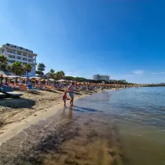 Słoneczna plaża w Golem, Albania, z leżakami, parasolami i hotelami. Idealne miejsce na wakacje, jedna z głównych atrakcji.