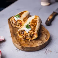Dwa soczyste rolady z mięsem i warzywami, polane sosem, tworzą pyszny kebab w tortilli. Idealny na szybki posiłek.