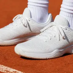 Białe buty tenisowe na ceglanym korcie, gotowe do gry.