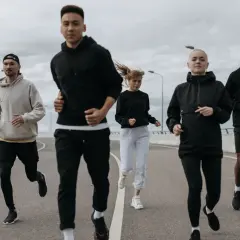 Grupa biegaczy w sportowych strojach. Idealny zestaw, jak się ubrać na bieganie 10 stopni: bluzy, spodnie i kurtki.