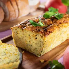 Pyszny pasztet z cukinii, lekki i aromatyczny, idealny na kanapki. Obok kromki chleba i pomidorów.