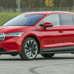 Czerwona Skoda Enyaq na tle zieleni. Sprawdź aktualną skoda enyaq cena i wybierz swój wymarzony samochód elektryczny.