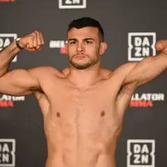 Fighter with one arm boxing, flexing his bicep. He stands against a backdrop of DAZN and Bellator MMA logos.