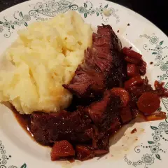 Un plat réconfortant de joue de bœuf à la bière, tendre et savoureuse, accompagnée d'une purée de pommes de terre onctueuse.
