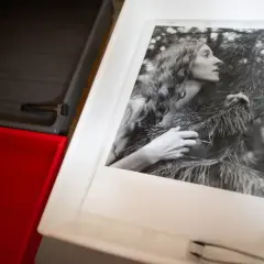 Kobieta w lesie na odbitce fotograficznej, która właśnie wyłania się z ciemni. Roztwór w ciemni fotograficznej czeka na kolejne etapy.