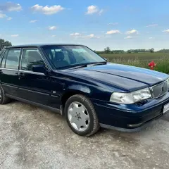 Granatowe Volvo S70, jeden z klasycznych modeli, stoi na szutrowej drodze.