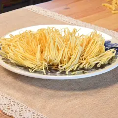 Talerz pełen cienkiego, żółtego makaronu pszennego, idealnego do przygotowania pysznego obiadu. Zastanawiasz się, ile makaron pszenny kcal ma porcja?