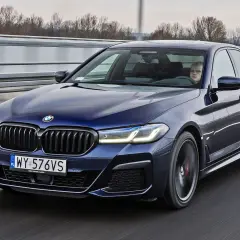 Ciemnoniebieskie BMW 520d xDrive jedzie autostradą. Kierowca z zaciekawieniem obserwuje drogę.