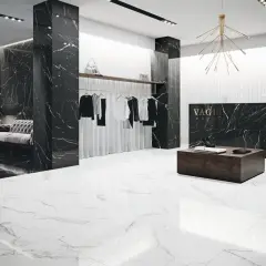 Elegancki butik z czarnymi ścianami w żyłach nero marquina i białymi podłogami. Wieszaki z ubraniami, kanapa i lada recepcyjna.
