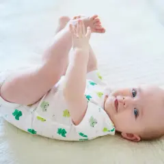 Ein Baby mit 6 Monaten kann schon viel! Dieses Baby liegt auf dem Rücken, hebt seine Beine und spielt mit seinen Füßen.