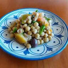Un'appetitosa insalata di ceci alla siciliana, con pomodoro, olive e verdure fresche, servita su un piatto decorato.