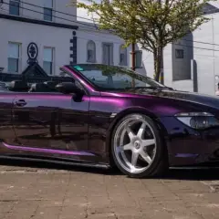 Fioletowe BMW E64 kabriolet z chromowanymi felgami stoi na ulicy.