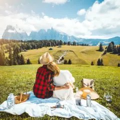 Para spędza **weekend majowy** na pikniku w górach, otoczona zielenią i majestatycznymi szczytami.