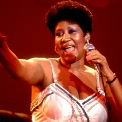 Aretha Franklin śpiewa na scenie, trzymając mikrofon. Jej dzieci z pewnością byłyby dumne z jej występu.