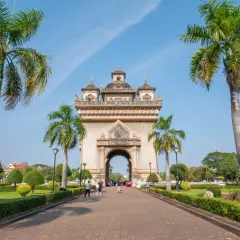 Łuk Triumfalny Patuxai, symbol stolicy Laosu, Wientianu, otoczony palmami i zielenią.