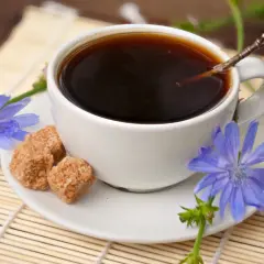 Aromatic kawa z cykorii, ozdobiona niebieskimi kwiatami i kostkami brązowego cukru, na bambusowej macie.