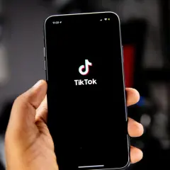 Dłoń trzyma smartfon z logo TikToka. Kiedy powstał TikTok? Aplikacja zadebiutowała w 2016 roku.