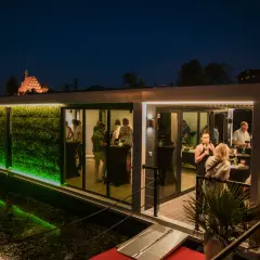 Nowoczesna restauracja na wodzie w Bydgoszczy, z zieloną ścianą i ludźmi bawiącymi się wieczorem. Czy to najlepsza restauracja w Bydgoszczy?