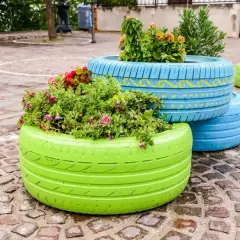 Kolorowe opony pomalowane na zielono i niebiesko służą jako donice. Dowiedz się, jak zrobić skalniak z opon!