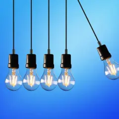 Cinque lampadine a filamento pendono da fili neri su sfondo blu. Una lampadina è staccata, suggerendo dove si buttano le lampadine esauste.