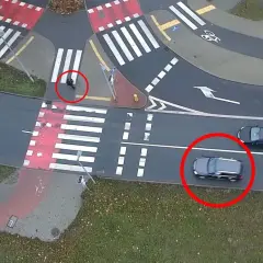 Osoba na przejściu dla pieszych, samochody czekają.