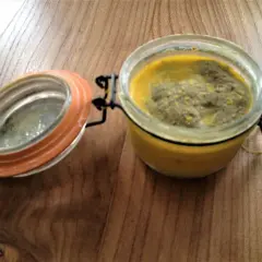 Terrine le parfait recette : un pot en verre avec un couvercle orange ouvert, contenant une préparation jaune et verte sur une table en bois.