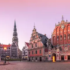 Ratusz i Dom Bractwa Czarnogłowych w Rydze, z wieżą kościoła św. Piotra w tle, o wschodzie słońca.