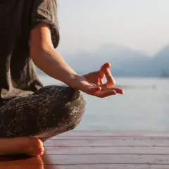 Persona meditando en posición de loto, con la mano en mudra Gyan, susurrando el mantra om.