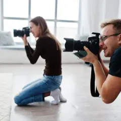 Mężczyzna i kobieta uczą się, jak zostać fotografem, ćwicząc z aparatami w studiu.