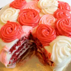 En skivad red velvet cake med fluffig frosting i rosformar i rött och vitt.