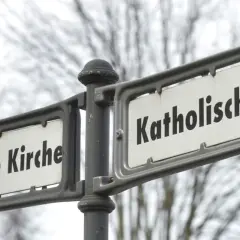 Straßenschilder zeigen "Evangelische Kirche" und "Katholische Kirche". Ein deutlicher Unterschied katholisch evangelisch, der die Vielfalt der Glaubensrichtungen symbolisiert.