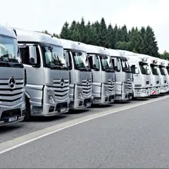Rangée de camions Mercedes-Benz argentés et blancs, prêts pour le transport. La réglementation stationnement poids lourds est respectée.