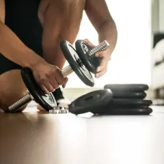 Un homme prépare ses haltères pour une séance de cardio boxing intense.