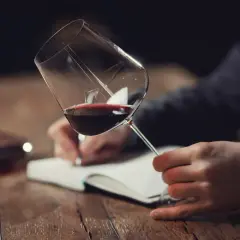 Un homme déguste un verre de vin rouge, notant ses impressions pour la saint-emilion grand cru classé liste.