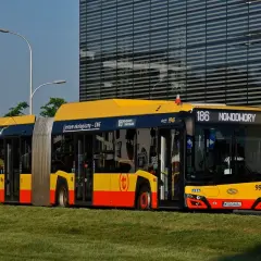 Autobus 186 linii Nowodwory w Warszawie, ekologiczny, zasilany CNG, stoi na tle nowoczesnego budynku.