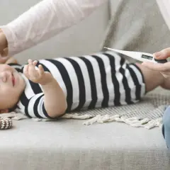 Mamma controlla la febbre al neonato di 1 mese con un termometro. 38.0°C.
