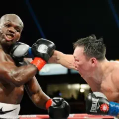 A boxer lands a punch on his opponent. The boxer on the left, with a determined grimace, is about to be hit. The boxer on the right, with a focused expression, delivers a powerful blow. This is a classic boxer vs brawler showdown.