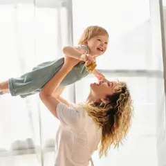 Radosna mama podrzuca dziecko do góry. To są te chwile, dla których warto żyć, prawdziwe babciowe dla kogoś.
